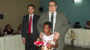Promotor de Justiça (à direita) e Juiz de Direito entregam tablet a uma das estudantes premiadas