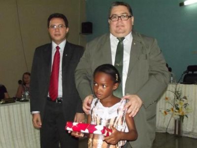 Promotor de Justiça (à direita) e Juiz de Direito entregam tablet a uma das estudantes premiadas