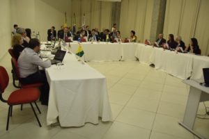 Foto: pessoas reunidas em torno de uma mesa em U, com bandeiras de todos os estados do Brasil. Reunião do CDEMP.