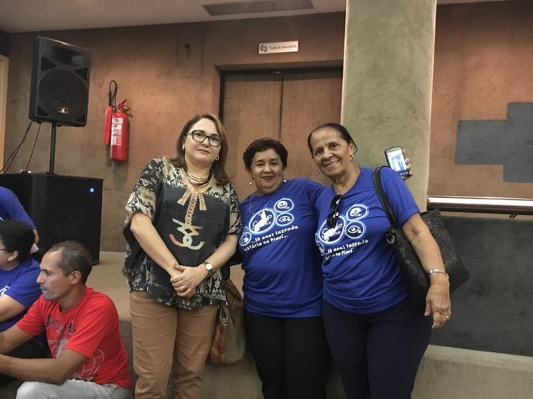 Três mulheres de pé sorrindo para foto