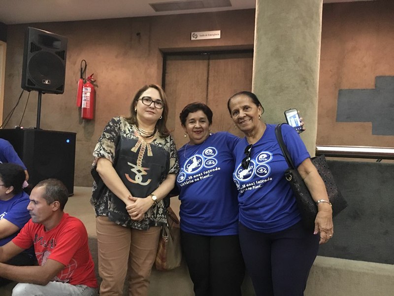 Três mulheres de pé sorrindo para foto