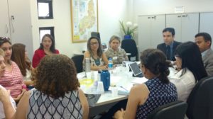 Pessoas sentadas em volta da mesa durante reunião