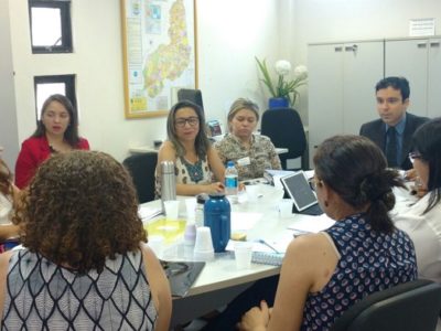 Pessoas sentadas em volta da mesa durante reunião
