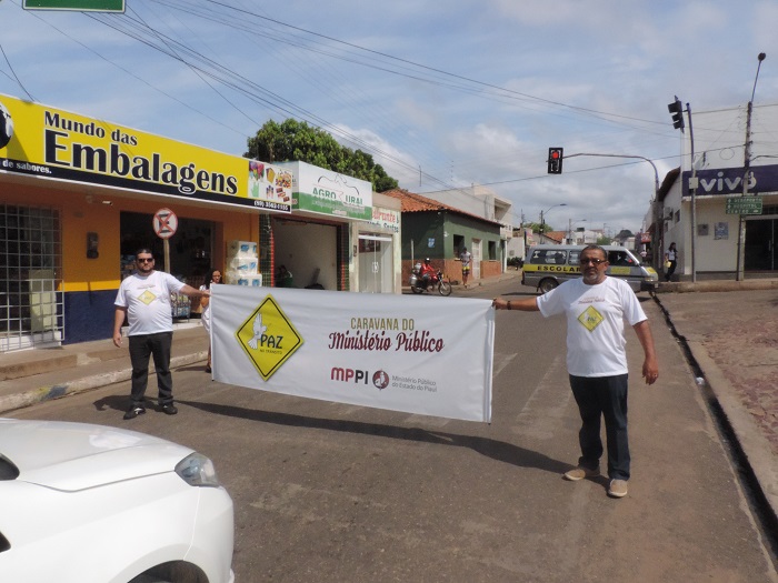 Duas pessoas segurando uma faixa em avenida 