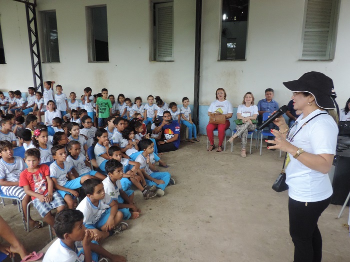 Pessoa de pé com alunos sentados ouvindo palestra 