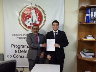 O promotor de Justiça Nivaldo Ribeiro, em pé, segura um documento junto com o vereador eleito.