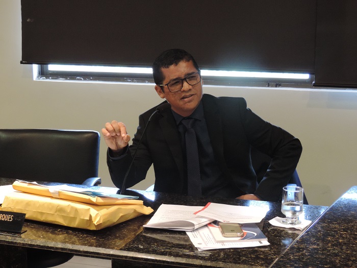 Promotor de Justiça Gerson Gomes fala ao microfone, sentado à mesa do plenário do Colégio de Procuradores de Justiça.