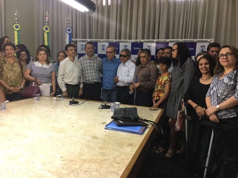 Grupo de pessoas de pé, sorrindo, durante uma solenidade.