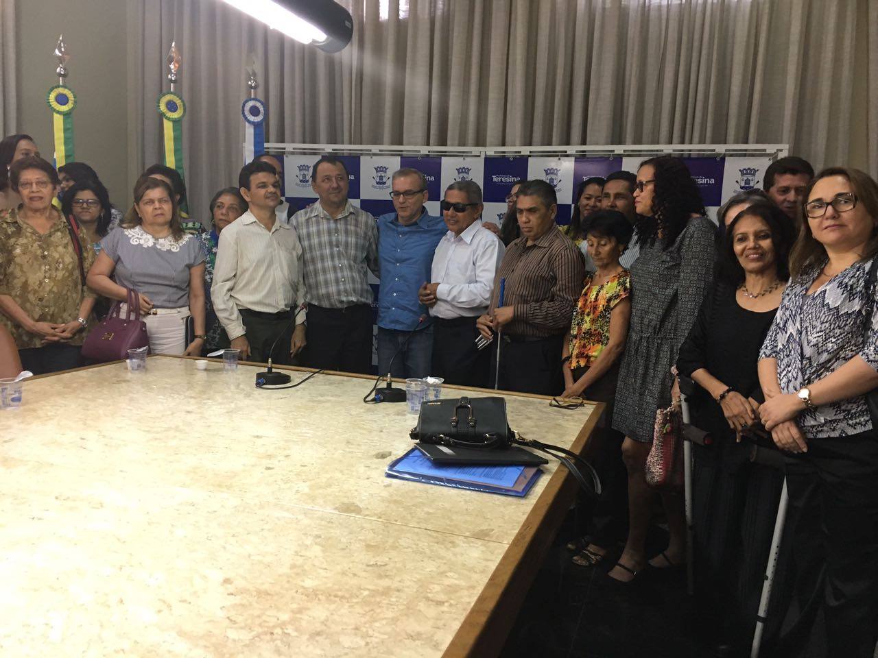 Grupo de pessoas de pé, sorrindo, durante uma solenidade.