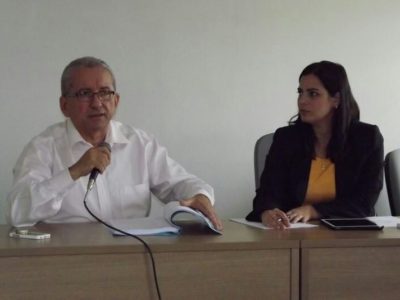 Promotores de Justiça sentados diante de um balcão, com microfones.