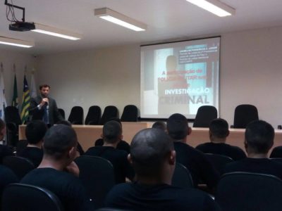 Promotor de Justiça de pé, diante de um auditório lotado.