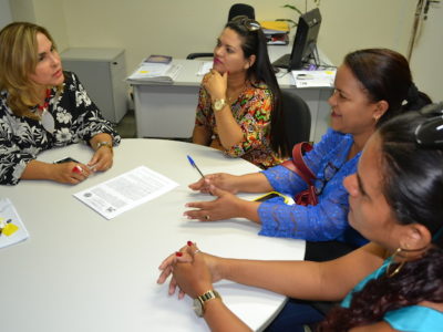 Mulheres em reunião ao redor de uma mesa.