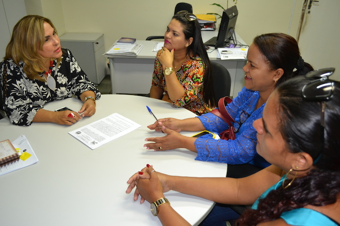 Mulheres em reunião ao redor de uma mesa.