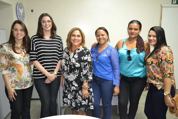 Mulheres posando de pé, sorrindo.