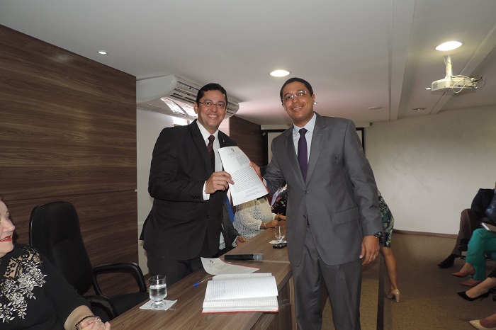 Promotor de Justiça empossado segura termo de posse junto com o Procurador-Geral de Justiça.