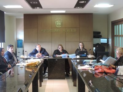 Pessoas reunidas, trabalhando, em torno da mesa do plenário de Procuradores de Justiça.