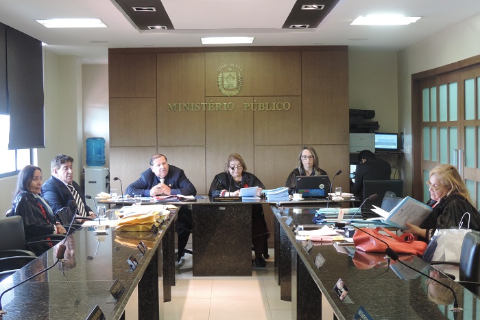 Pessoas reunidas, trabalhando, em torno da mesa do plenário de Procuradores de Justiça.