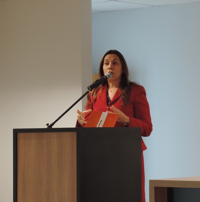 A procuradora Raquel Normando fala ao microfone, de pé diante de uma tribuna.