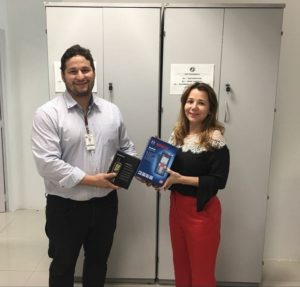 Duas pessoas segurando caixas e sorrindo pra foto