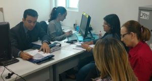 Pessoas sentadas olhando para um documento discutindo o mesmo