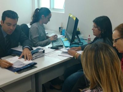Pessoas sentadas olhando para um documento discutindo o mesmo