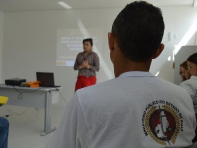Pessoa sentada com outra ao fundo falando durante curso