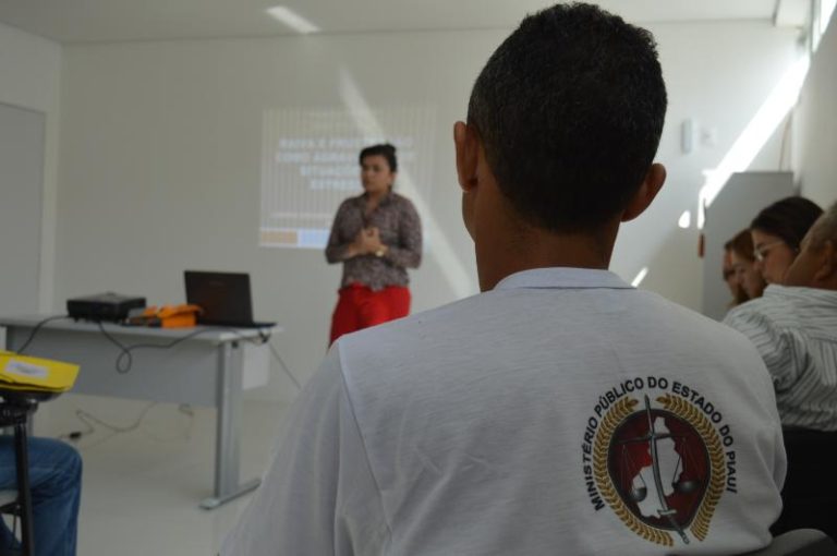 Pessoa sentada com outra ao fundo falando durante curso