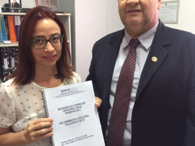 Promotora de Justiça entrega relatório nas mãos do Corregedor Geral, enquanto os dois posam para a câmera.