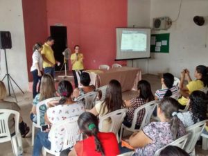 Promotora de Justiça fala ao microfone para agentes de endemia, sentados.