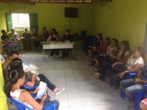 Muitas pessoas reunidas, sentadas em uma sala.