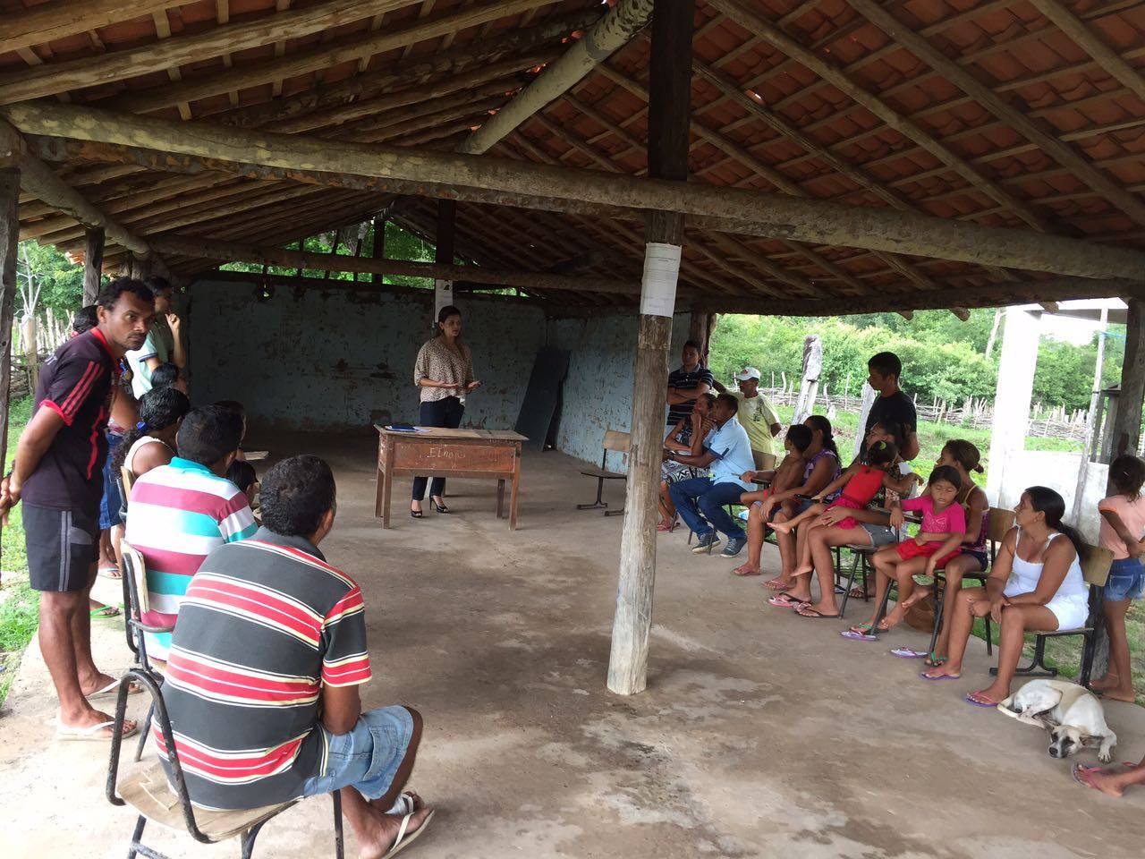 Promotora de Justiça coordena reunião com pais de alunos, em estrutura de taipa.