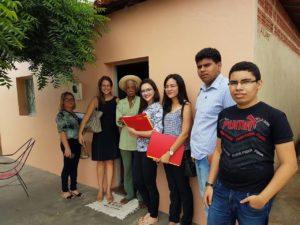 Equipe de inspeção reunida em frente de uma casa, com um senhor idoso na porta.