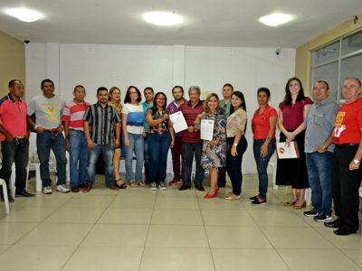 Cerca de quinze pessoas sorrindo, de pé.