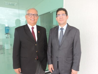 Dois homens de pé, com terno, posando para a câmera.