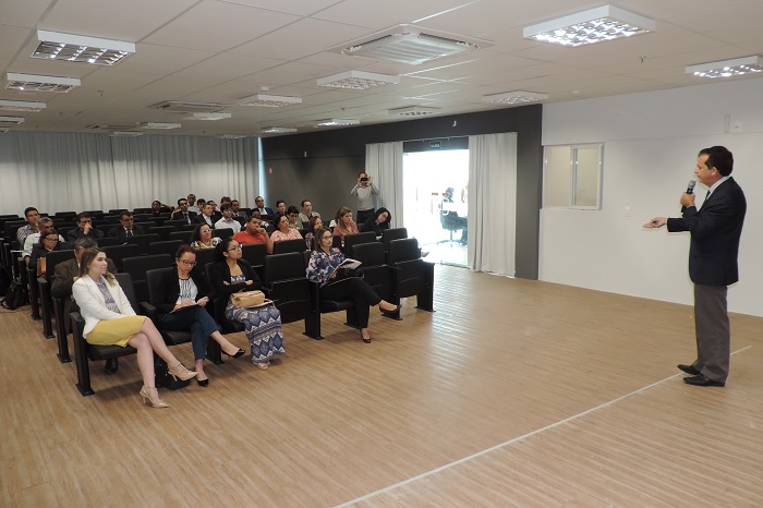 Pessoas sentadas assistindo palestra e um homem de pé falando