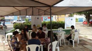 Estandes montados em praça, com várias pessoas sendo atendidas.