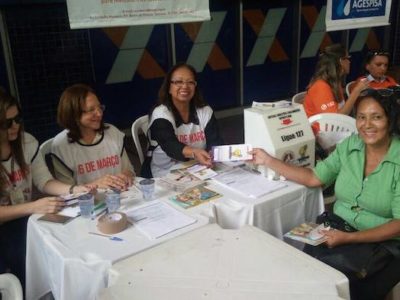 Ouvidora do MPPI entrega folheto informativo para cidadã durante atendimento em praça pública.
