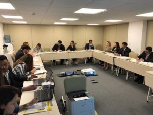 Pessoas sentadas em torno de uma mesa em formato de U.