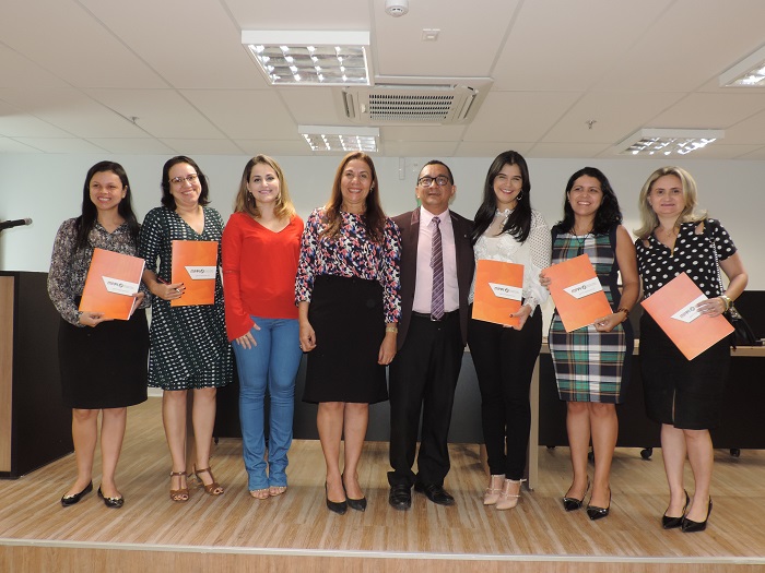 Pessoas de pé segurando documento e sorrindo para fotografia