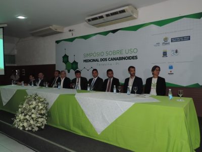 Autoridades sentadas em mesa de honra de evento.