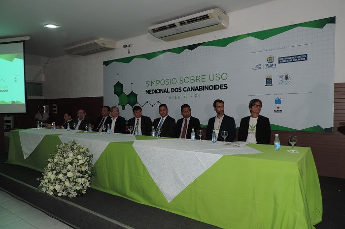 Autoridades sentadas em mesa de honra de evento.
