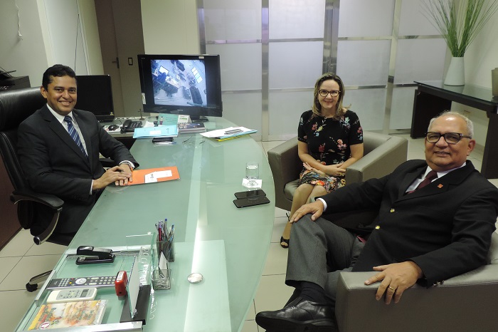 Três pessoas em torno de uma mesa.