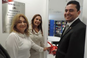 Três pessoas segurando uma fita e sorrindo para foto