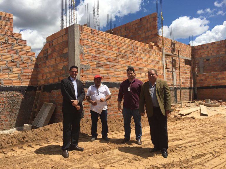 Quatro pessoas posam de pé em um canteiro de obras.