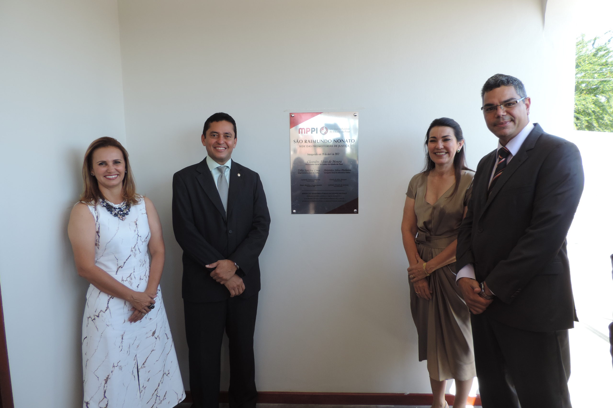 Pessoas de pé ao redor de uma placa de inauguração 