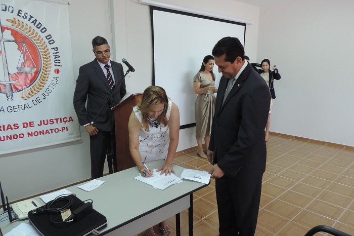 Mulher assinando um documento enquanto um homem a observa 