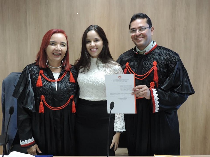 Três pessoas de pé sorrindo pra fotografia