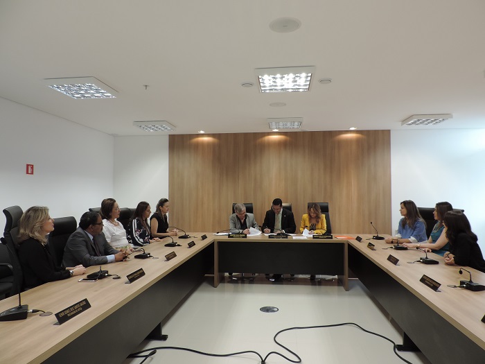 Pessoas sentadas em volta de uma mesa em formato U