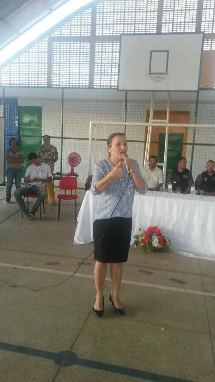 Mulher de pé segurando microfone e gesticulando 