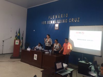 Pessoa falando no microfone com pessoas ao lado